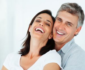 man standing behind woman smiling and leaning into him