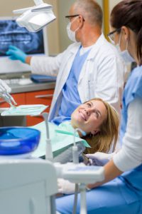 woman in dental exam room with hygienist and dentist